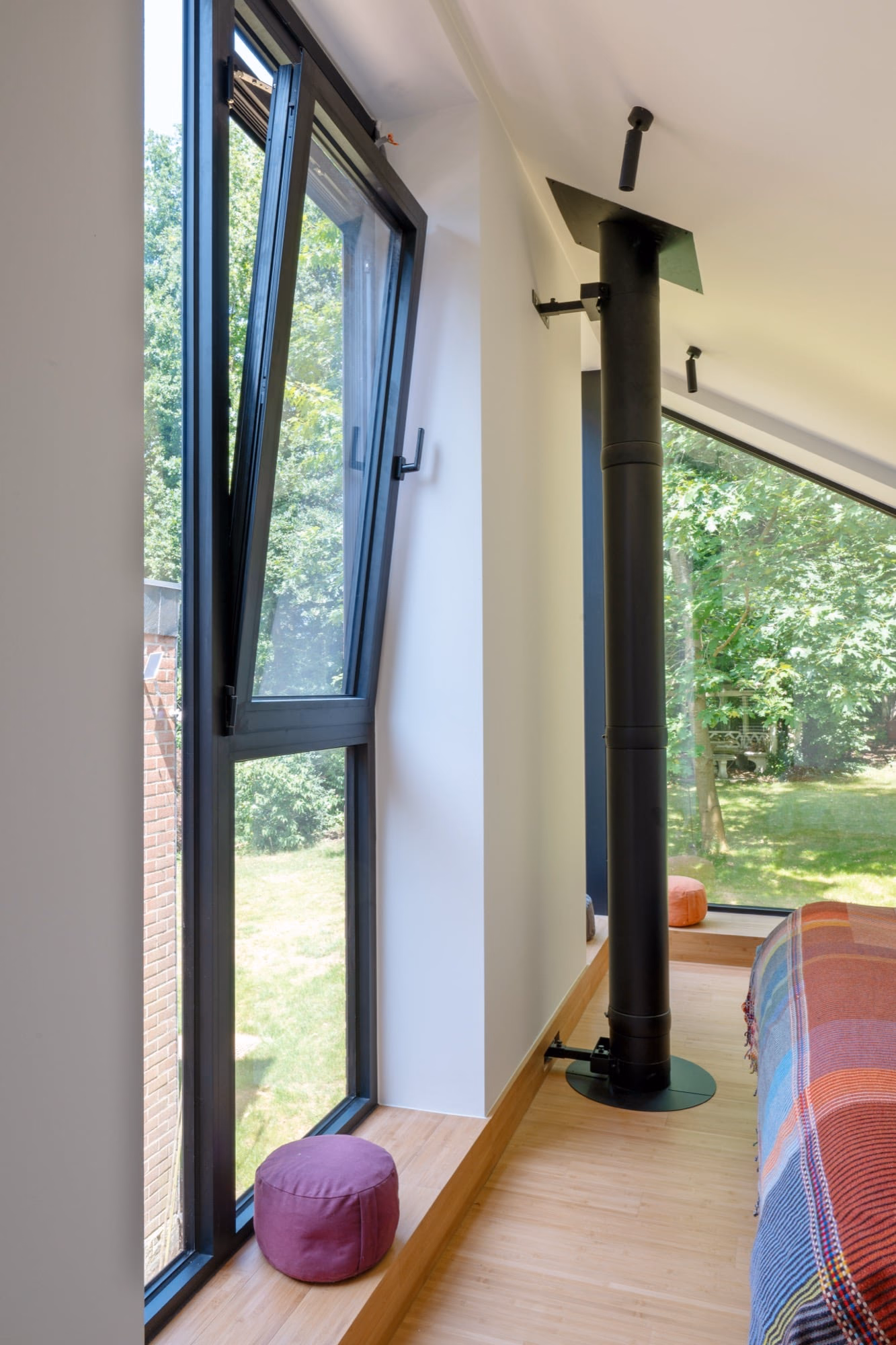 A room with a large window and a black chimney flue