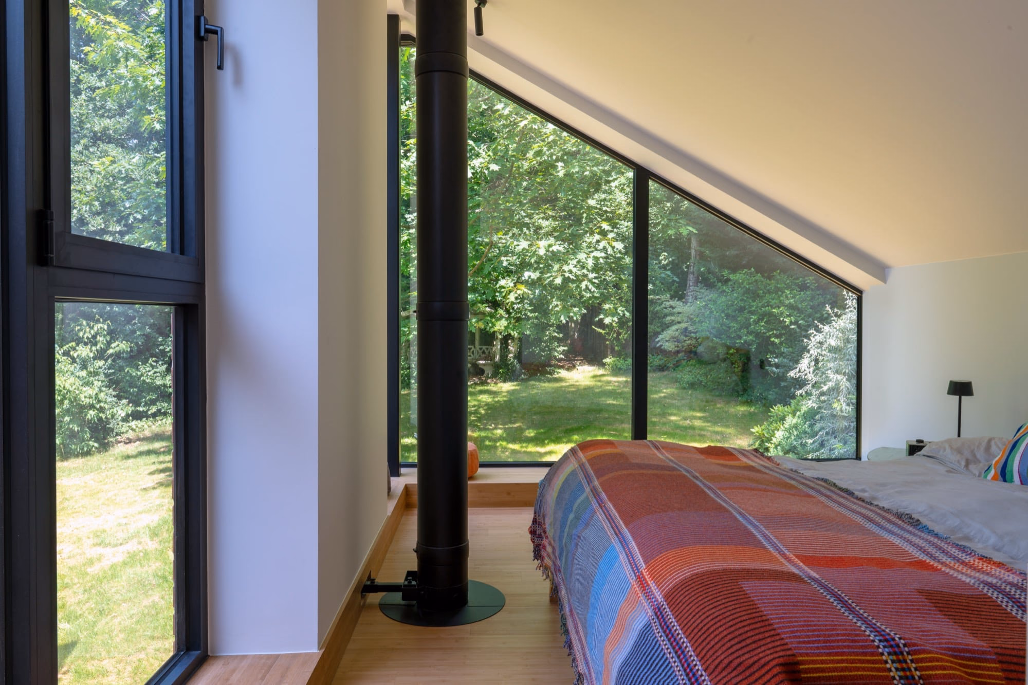 A bedroom with a large window and a tartan blanket