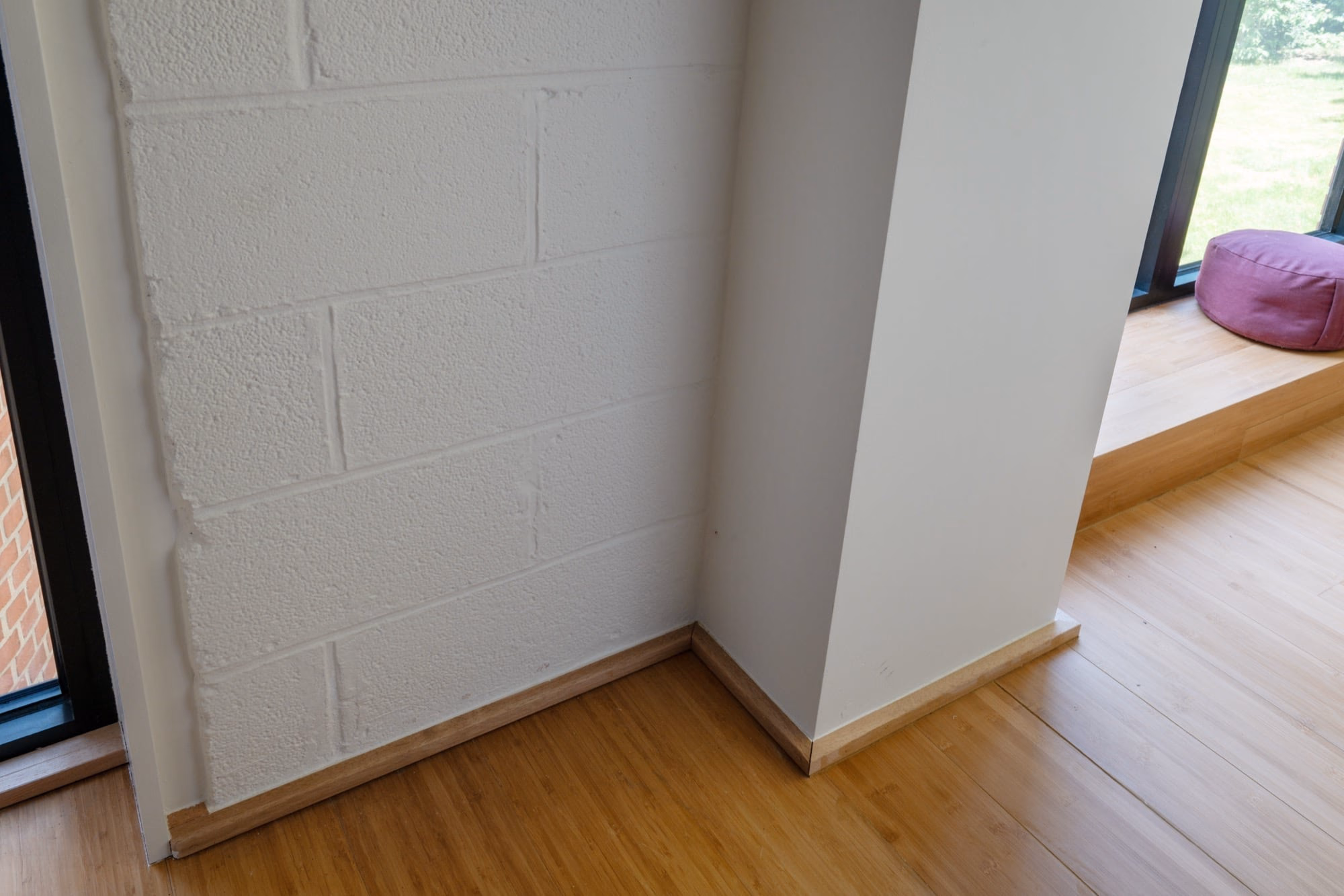 A corner with a white brick wall and a wooden floor