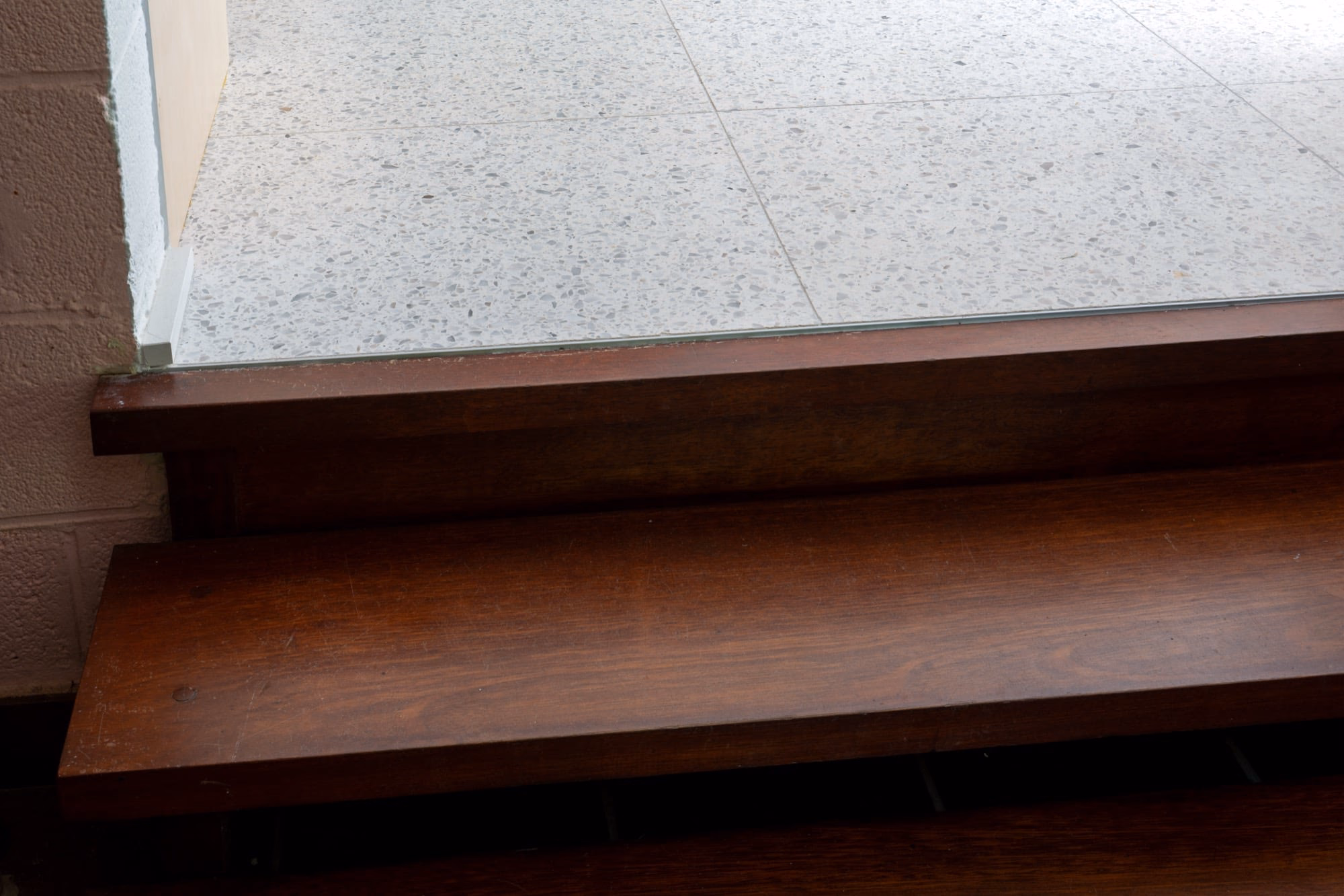 A wooden staircase leading down to a tiled floor