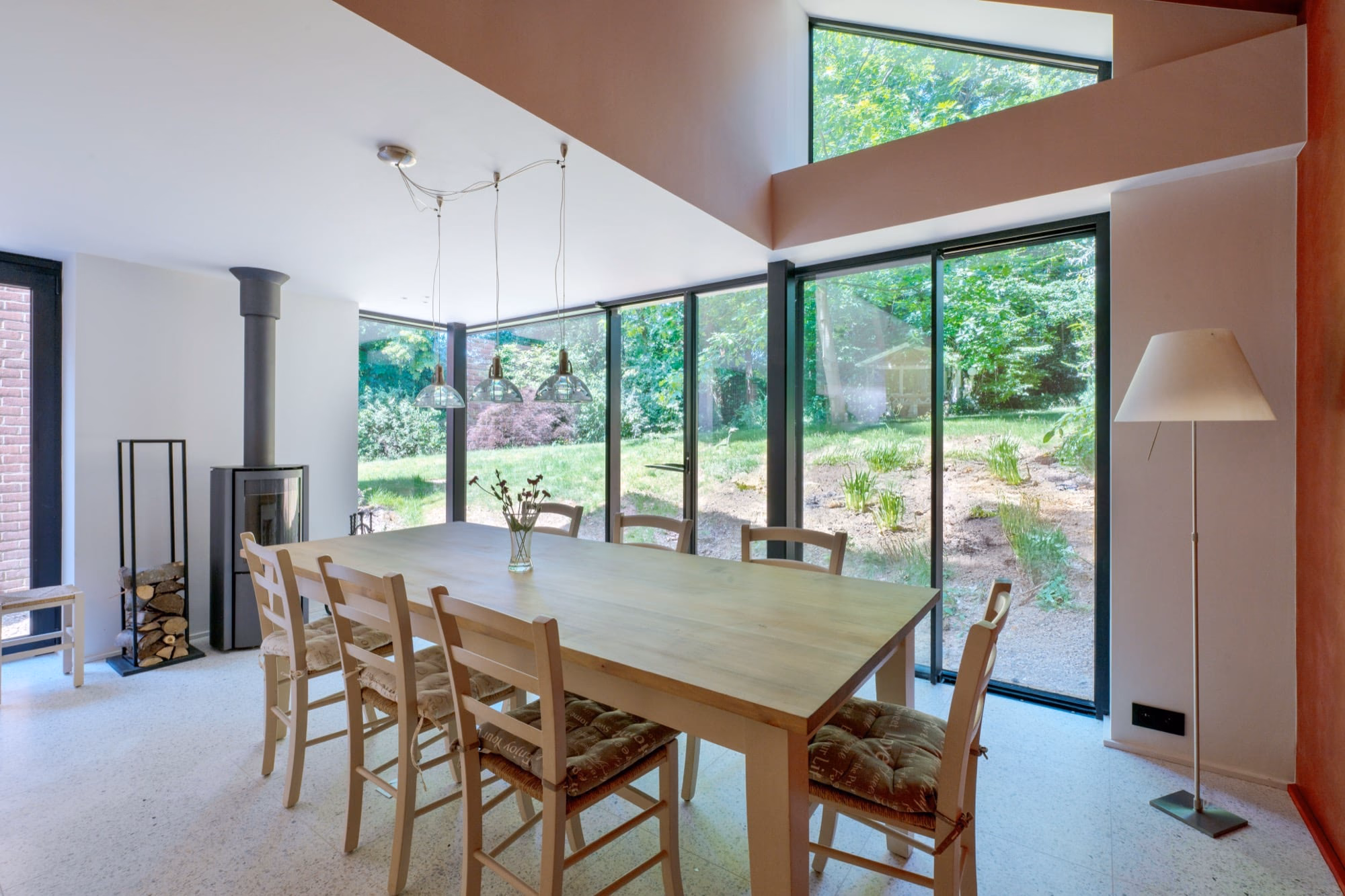 A dining table and chairs with a vase of flowers