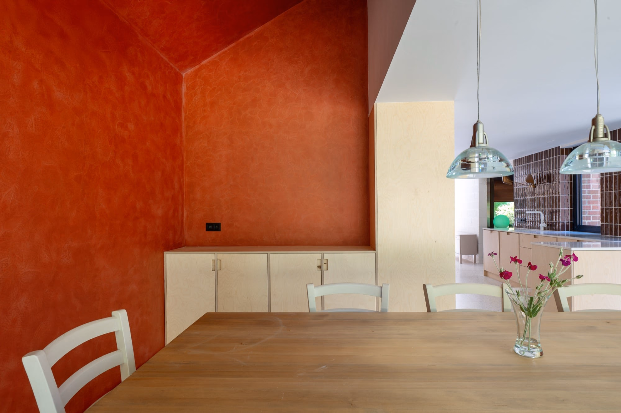 A dining table and chairs against a red wall