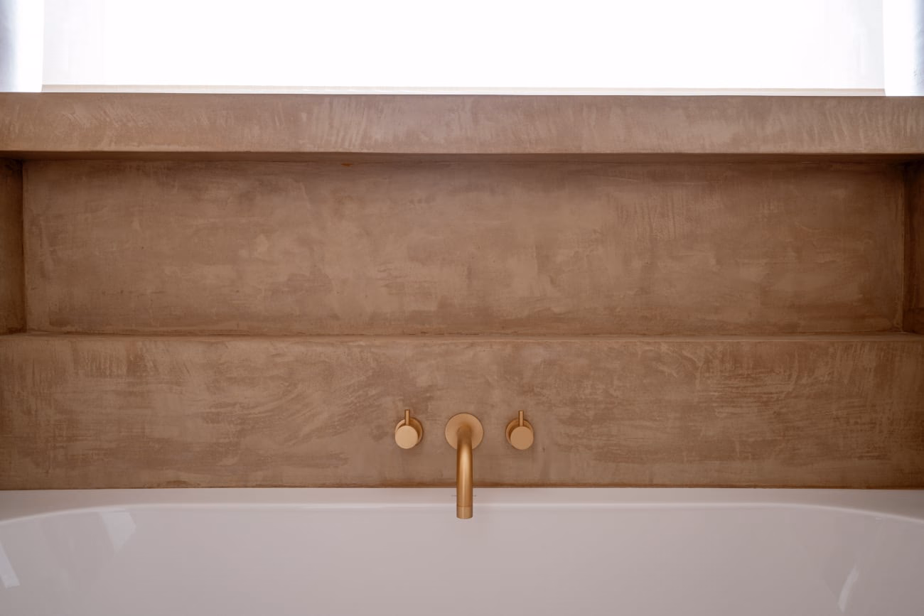 A washbasin with a wall-mounted brass tap